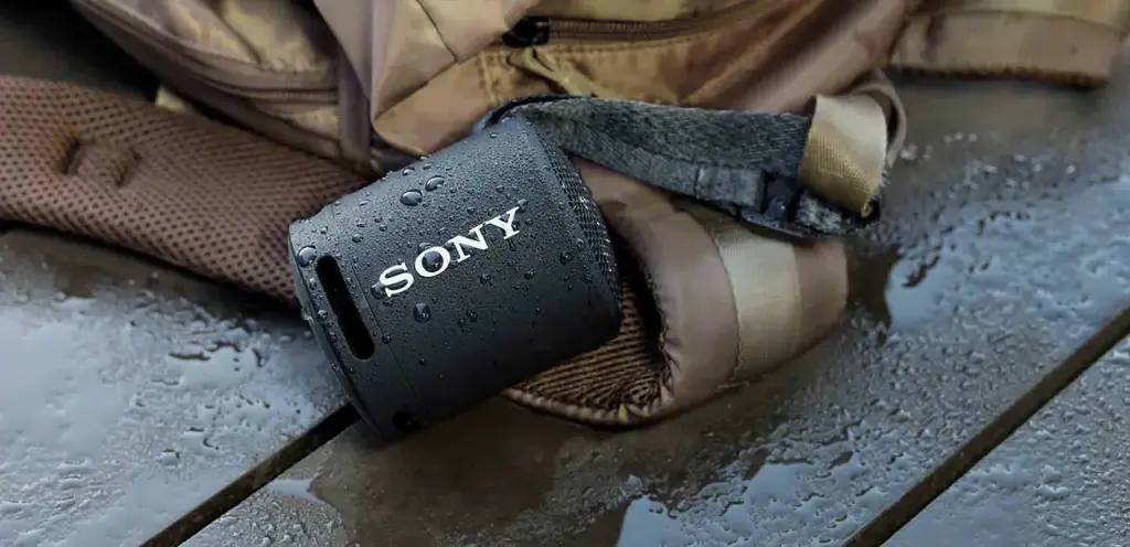 Schwarzer Sony Bluetooth-Lautsprecher mit Wassertropfen auf einer nassen Oberfläche.