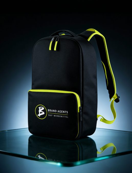 Schwarzer Rucksack mit gelben Reißverschlüssen und dem Logo von Brand Agents auf der Vorderseite.